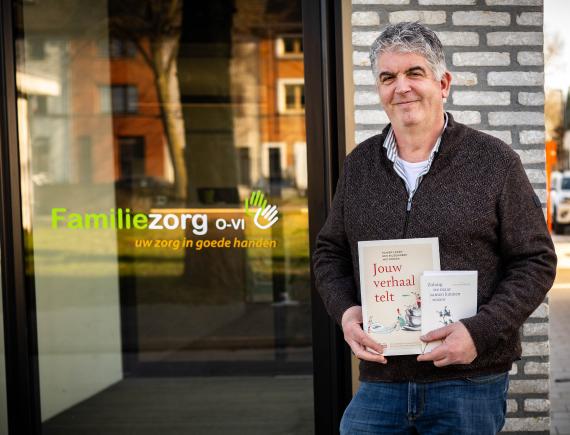 Dirk Terryn met zijn boeken voor het gebouw van Familiezorg O-Vl.
