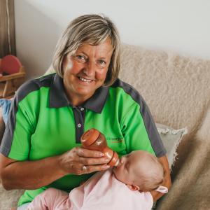 Verzorgende met baby op de arm